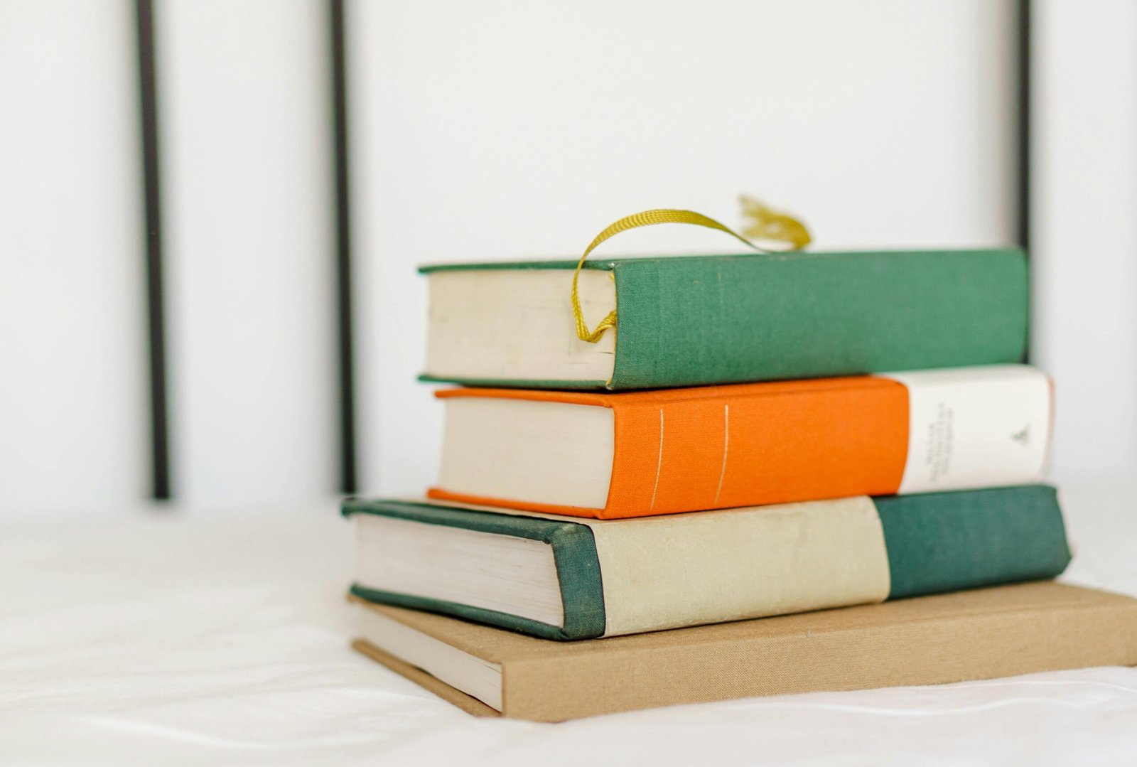 Close-up of a neatly stacked pile of hardcover books on a desk.