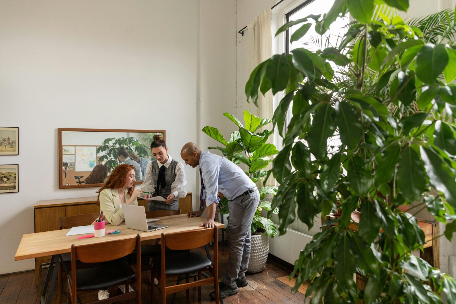 A diverse group of professionals collaborating in a modern office with greenery.